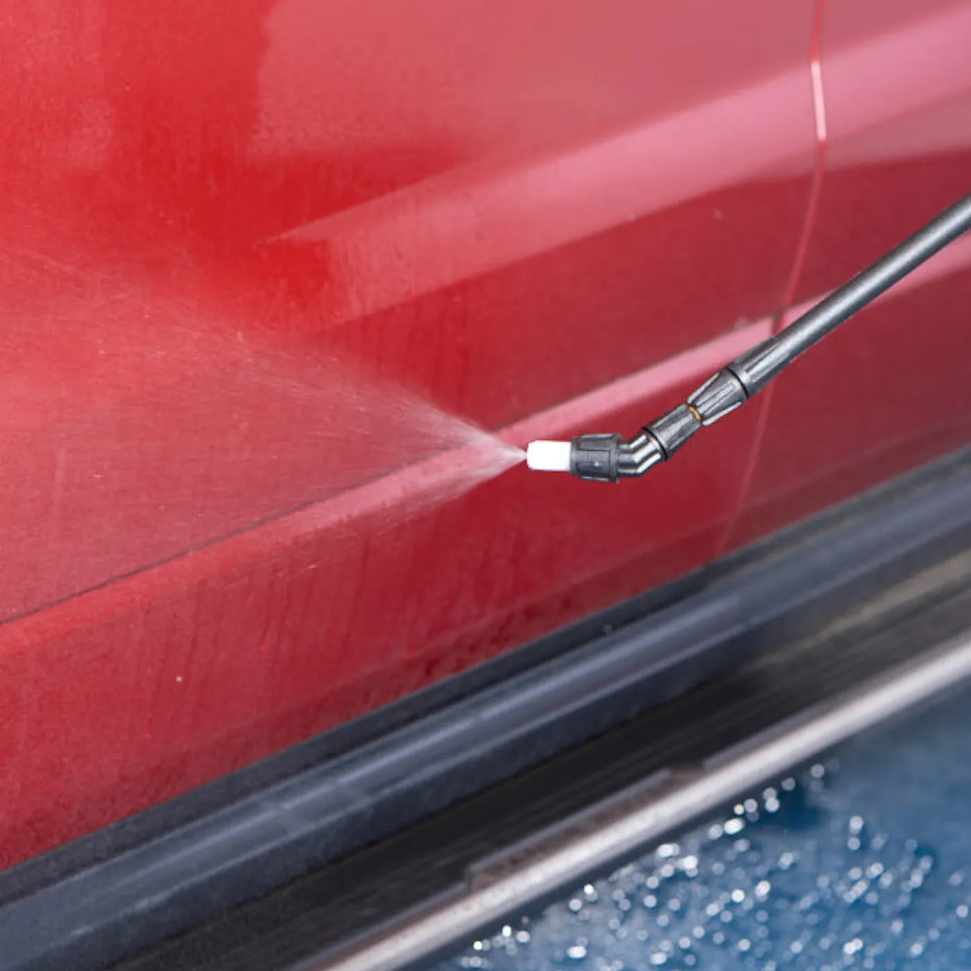 High-pressure water gun cleaning a red car