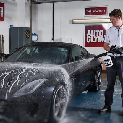 Person washing a black car with AUTO GLYMO products in a garage setting.