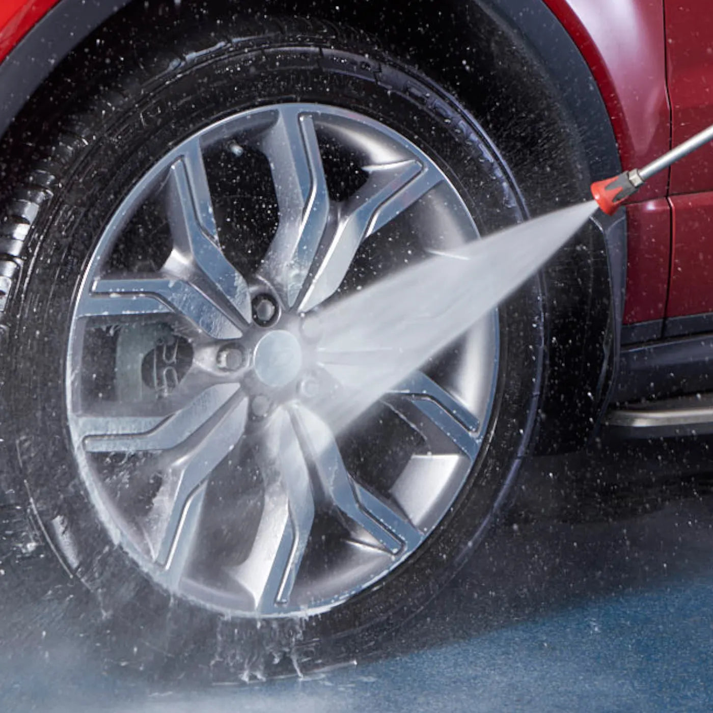Car wheel being cleaned with a high-pressure water hose