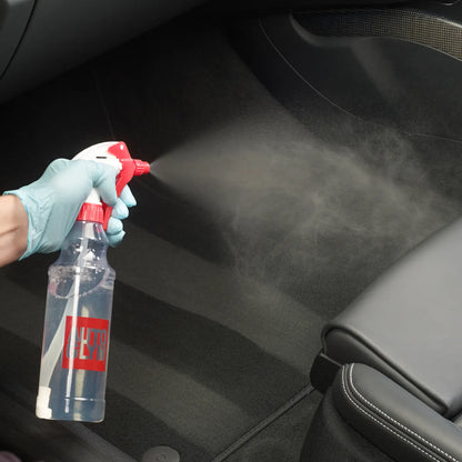 Person cleaning car interior with a spray bottle labeled 'DEET'.