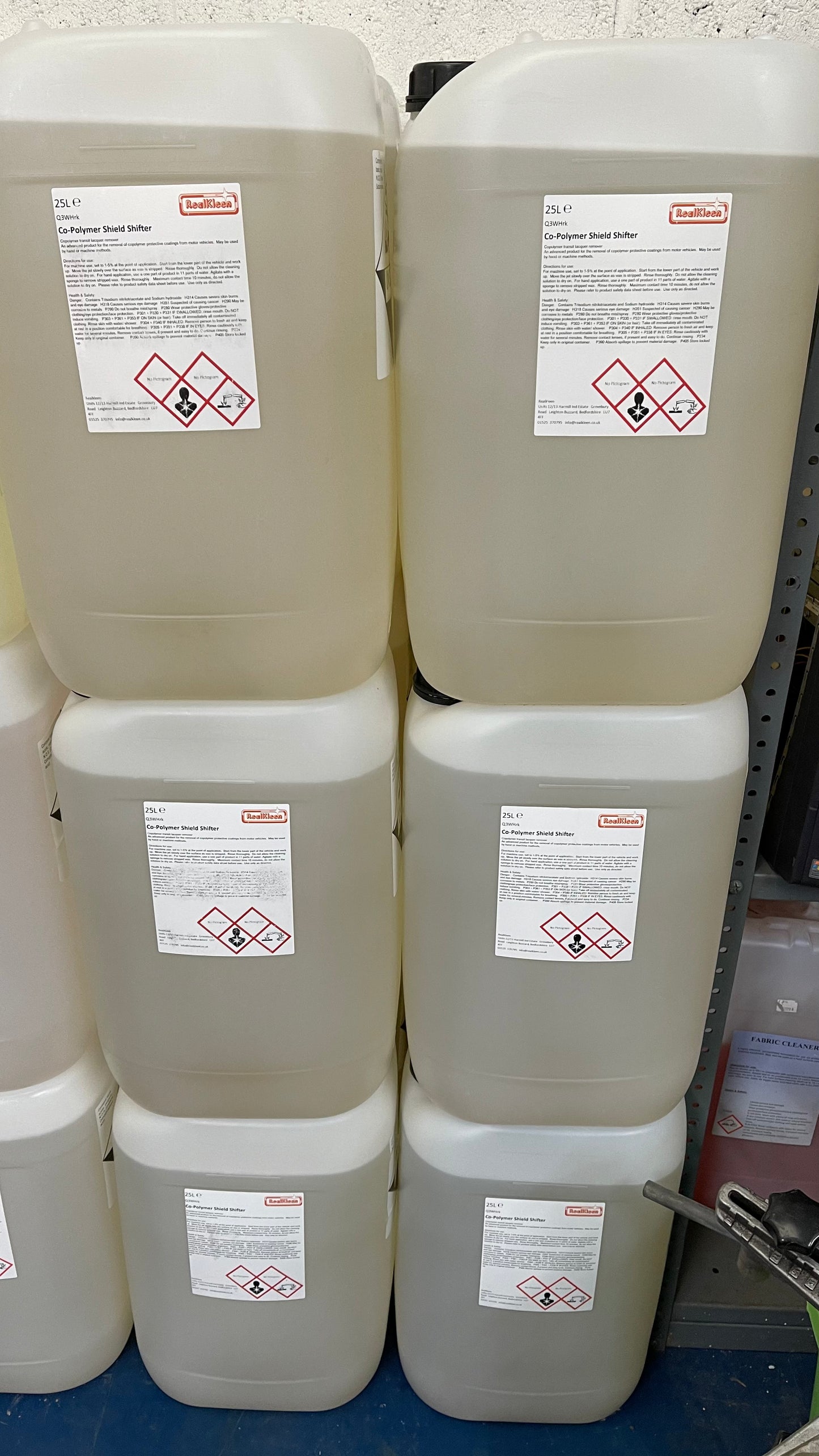 Stack of large white containers with hazard labels on a blue surface