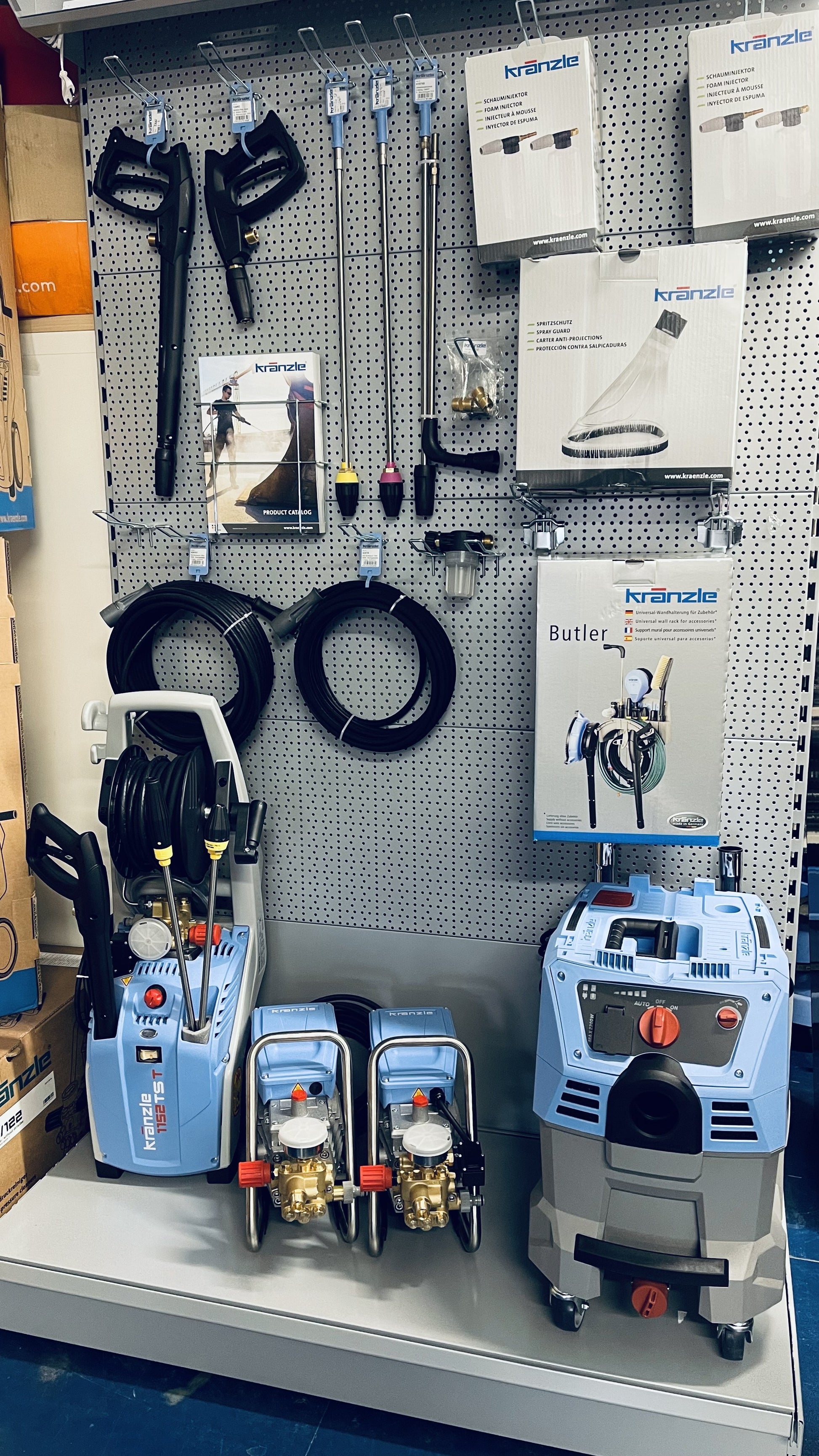 Display of pressure washers and cleaning tools on a pegboard wall.