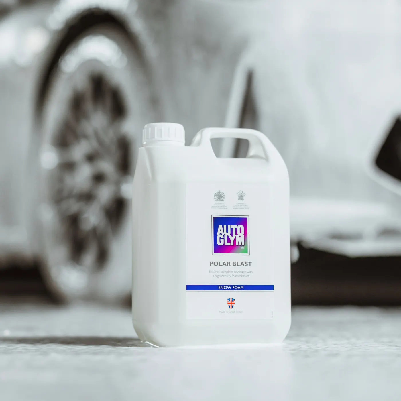 White car care product container with 'Autoglym' branding in front of a blurred car.