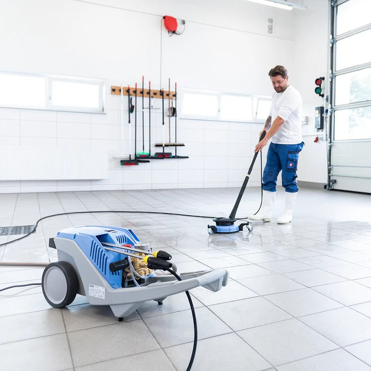Person using a floor cleaning machine in a garage setting